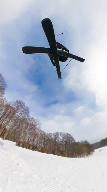 A wide angle directly below view of a freestyle skier doing a jump on a sunny day.