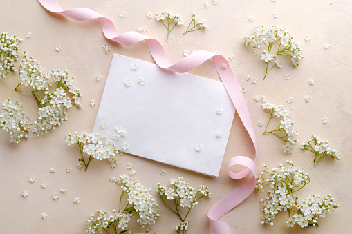 Flowers composition. Pink paper blank, rose flowers on pastel blue background. Valentines day, mothers day, womens day, spring concept. Flat lay, top view, copy space, square