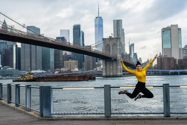 a woman jumping for joy in brooklyn after great training - east river audio imagens e fotografias de stock