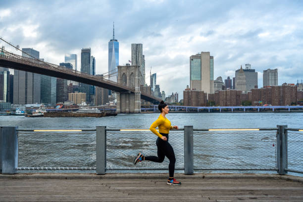 a fit woman enjoys her regular running session in brooklyn - east river audio imagens e fotografias de stock