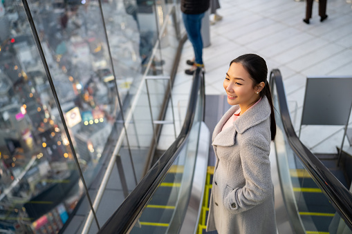 Portrait of Young Asian woman travel at skyscraper building rooftop in Shibuya, Tokyo city, Japan at sunset. Attractive girl enjoy outdoor lifestyle travel city on autumn winter holiday vacation.
