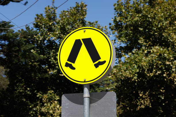 Close- up on a yellow metal street sign alerting drivers to a pedestrian crossing.