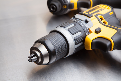Yellow cordless electronic screwdriver drill  on a stainless steel table