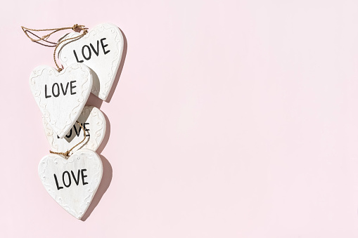 Wooden decoration in shape of hearts and word Love on pastel pink background, copy space, top view
