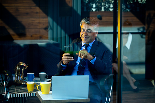 Businessman messaging using mobile phone at coffee shop