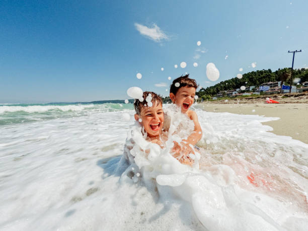 Young boys playing with waves Photo of two young boys rushing into the sea water and having fun with waves only boys stock pictures, royalty-free photos & images