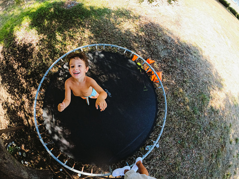 Photo of a cute, smiling, little boy jumping on a trampoline