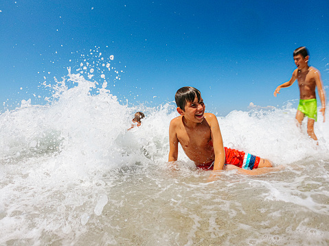 Photo of young boys rushing into the sea water and having fun with waves