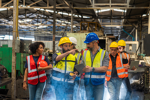 Team Workers and workers are standing in the factory. Group Staff Standing In Engineering Factory.