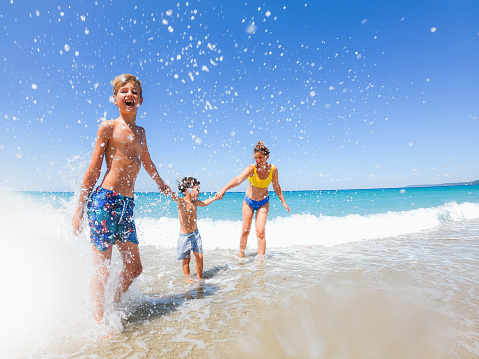 Photo of two young boys and their mom having fun on local beach during summer vacation