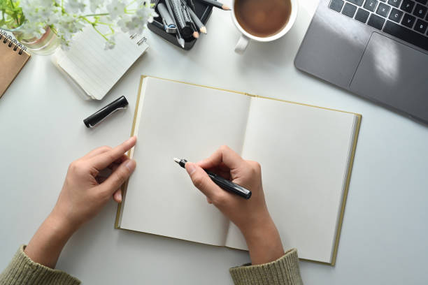 istock Overhead view of woman holding pen writing on blank notebook, makes important notes or agenda plan. 1462499379