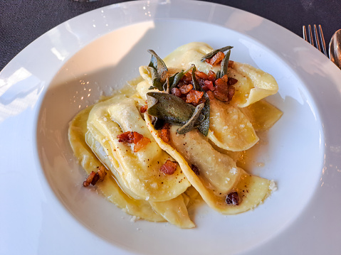 Casoncelli is a kind of ravioli, home made traditional food of the Bergamo, Italy. Delicious Italian food. Casoncelli cooked topped with parmesan cheese, melted butter and bacon