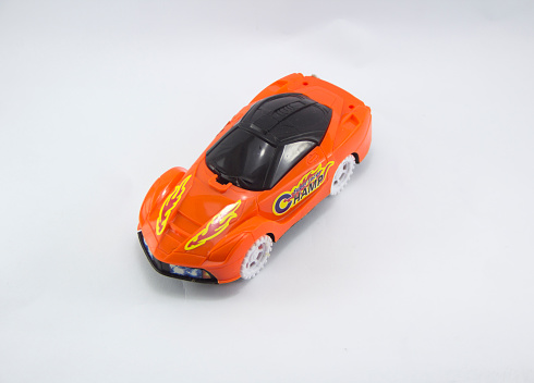 Close up of a children's toy mini racing car with an orange body and white tires