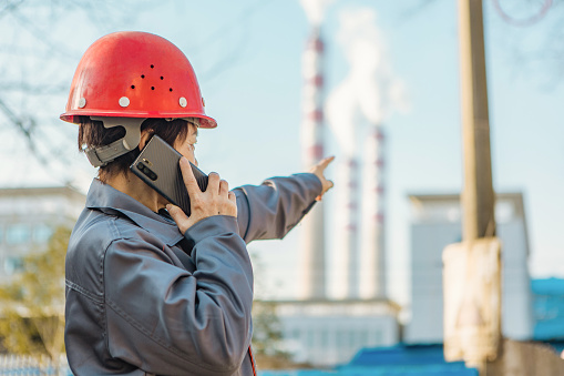 A female worker works in the power plant and makes a phone call