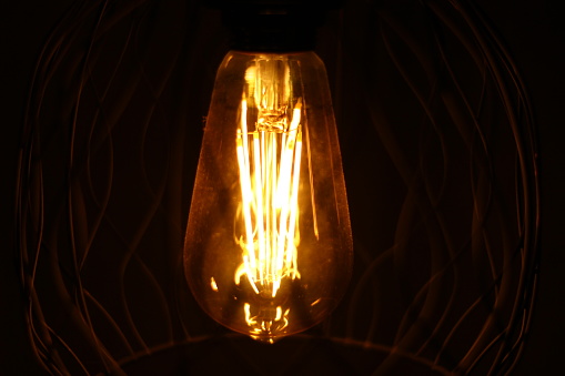 A scenic shot of a vintage light bulb illuminated in the darkness