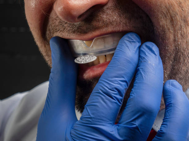 istock Unrecognizable Caucasian man with blue glove putting on a dental aligner. 1462527902