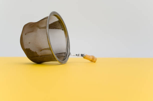 worn metal tea strainer on a yellow paper background