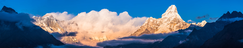Mt. Everest, Nuptse and Lhotse glowing in the golden light of sunset overlooked by Ama Dablam guarding the Khumbu valley high in the Himalayan mountains of Nepal.