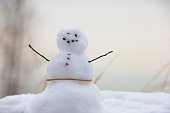 Closeup shot of a cute small snowman with rock eyes, buttons and twig arms