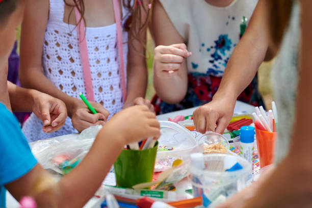 Children paper crafting with parents in outdoor children party, painting, molding of plasticine Children paper crafting with parents in outdoor children party, painting, molding of plasticine and making figures cut from paper. Children hobby paper craft modeling, group development of children kid stickers stock pictures, royalty-free photos & images