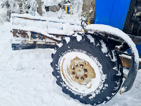large wheels of a blue tractor in a snowy forest. the concept of all-terrain transport in winter. Off-Road Vehicle