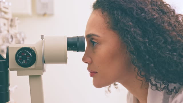 Optometry, vision and woman with a machine for healthcare, eyes and opthalmology. Clinic, consultation and optometrist looking through a lens for glaucoma check, diagnosis and visual test at work