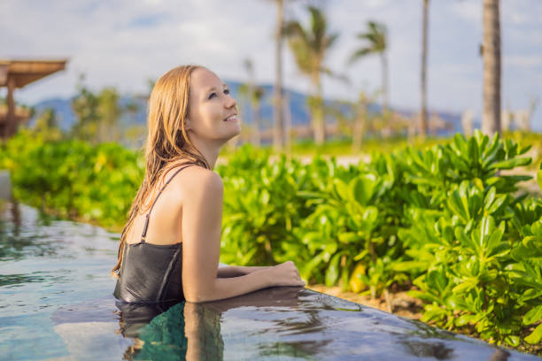 istock Woman relaxing in infinity swimming pool looking at view 1462555258
