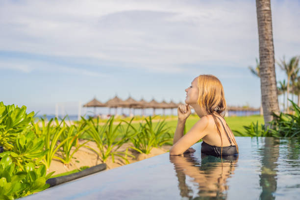 istock Woman relaxing in infinity swimming pool looking at view 1462555299
