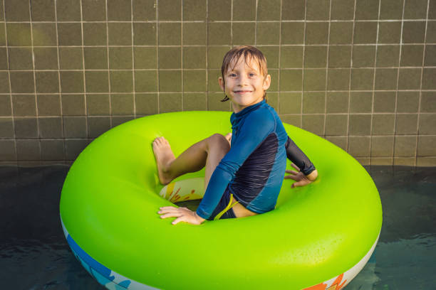 Playful Boy Relaxing in Swimming Float in Pool, looking at camera
