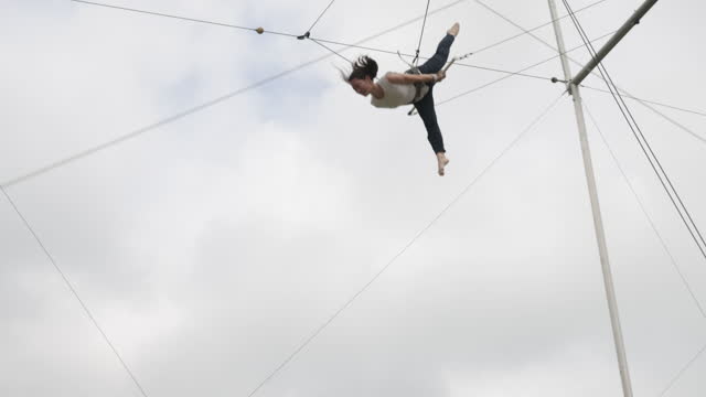 Young female trapeze artist flying in the sky