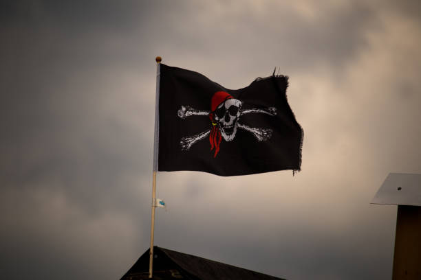 istock Low angle shot of a waving pirate flag with a skull under storm clouds 1462563428