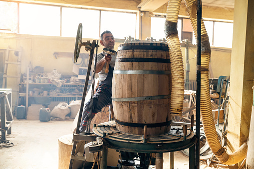 At the wood workshop, a Caucasian male barrel maker, burning an oak barrel, so the wood can gain aroma