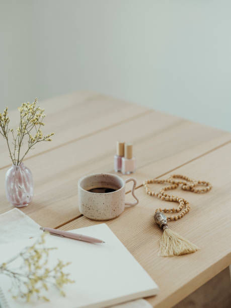 Modern still life at home coffee cup note book zen buddha necklace and pen on table