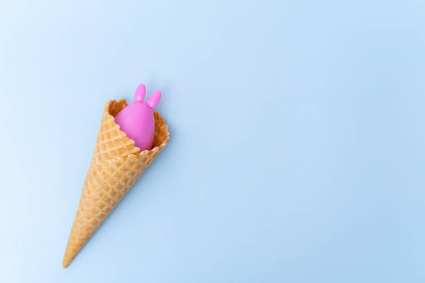 istock A waffle ice cream cone with a hidden pink Easter egg with ears like a bunny on a blue background 1462592108