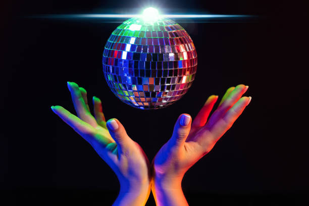 istock Female hand holding spinning disco mirror ball under neon. Glossy silver sphere 1462593004
