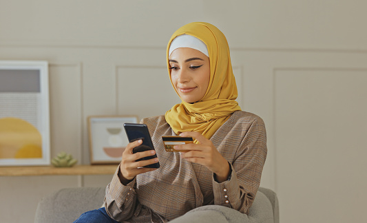 Credit card, muslim or woman with phone on online shopping or payment, internet purchase or ecommerce in living room. Fintech, happy or Islamic girl hands on smartphone for trading, banking or invest