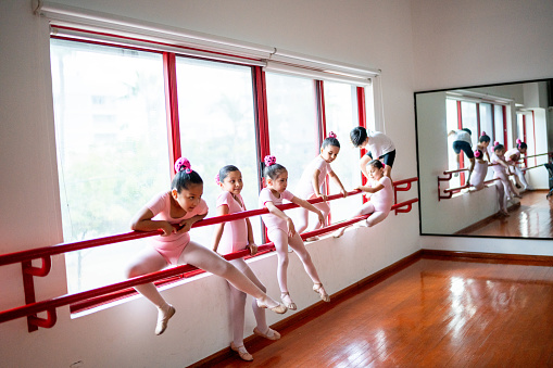 Ballet dancers climbing barre at the dance studio