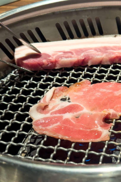istock Grilling pork belly meat on a round BBQ net in restaurant for eating. 1462615129