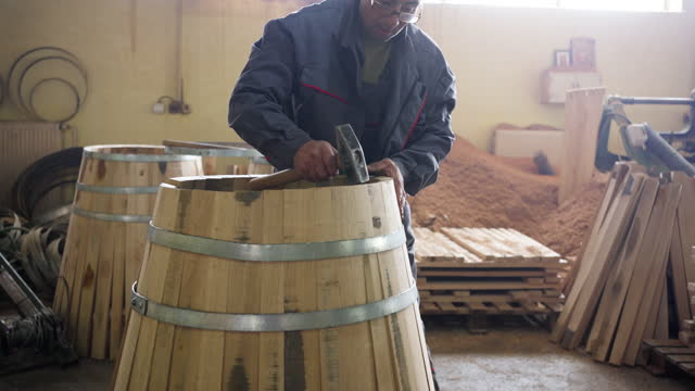 Cooper making barrel from oak wooden steves