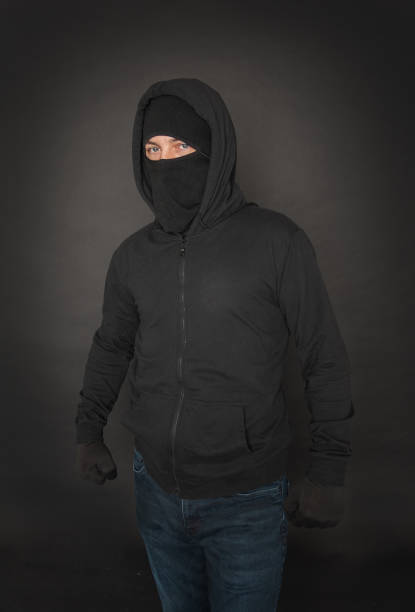 Unrecognizable man in the black hoody with hood wearing balaclava mask stock photo