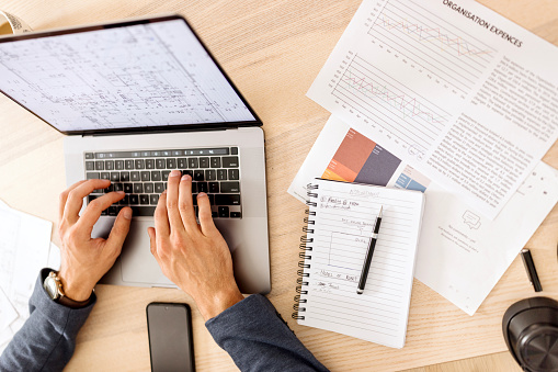 Overhead view of a laptop and some papers with a business chart on it