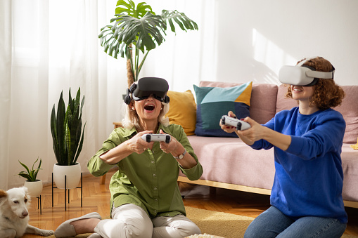 Grandmother spends some fun and exciting time with her granddaughter playing virtual reality games