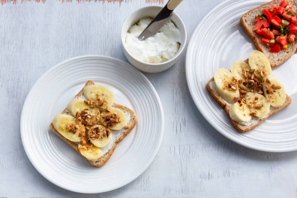 istock Sandwich breakfast has banana cream cheese almonds and tomato on white wood table. 1462644890