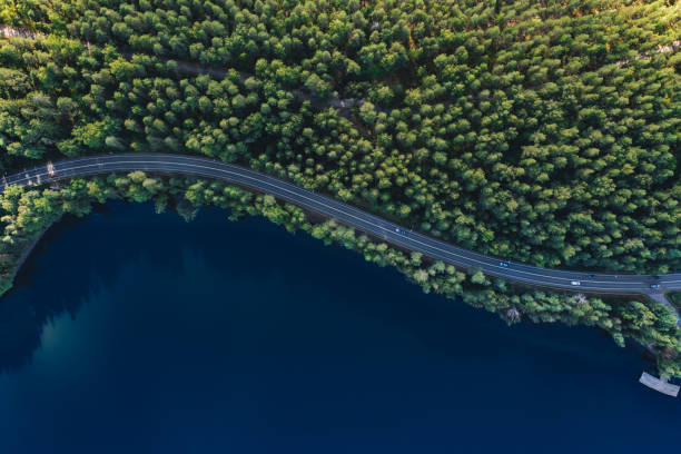 Aerial view of road with green woods by blue lakes water in Finland. stock photo