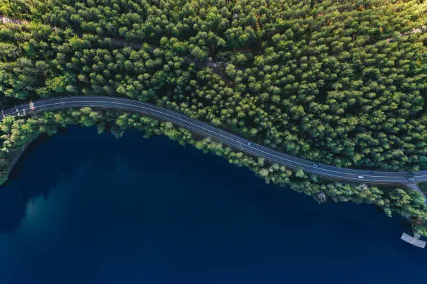 Photo of Aerial view of road with green woods by blue lakes water in Finland.