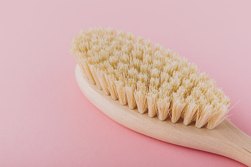 Massage brush. Natural wooden brush for body massage on pink background. Eco-friendly lifestyle concept and zero waste
