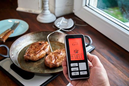 Food Safety - Checking the Right Temperature with Digital Thermometer on Roasted Pork Chops in a Pan