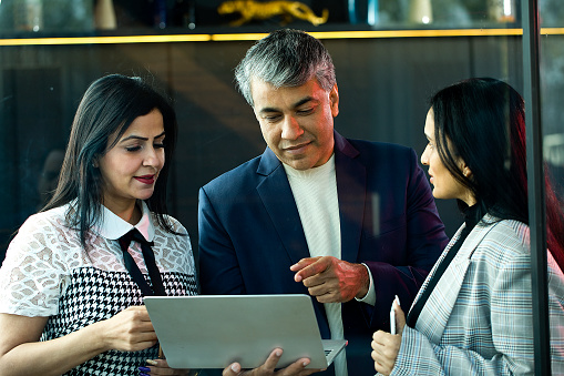 Three business colleagues having fun working together using laptop at office