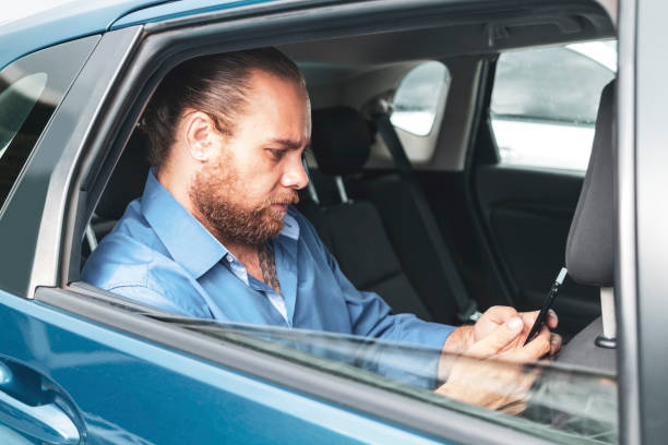istock Businessman in a car using smartphone. 1462655978
