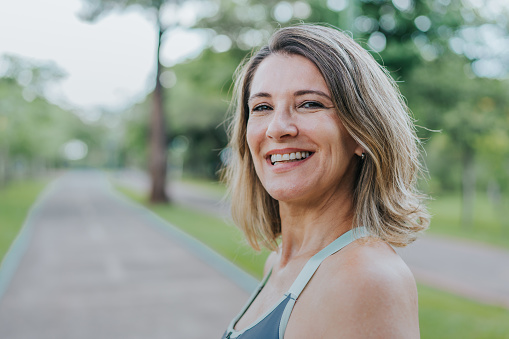 Joyous woman clenching fist while celebrating against isolated background